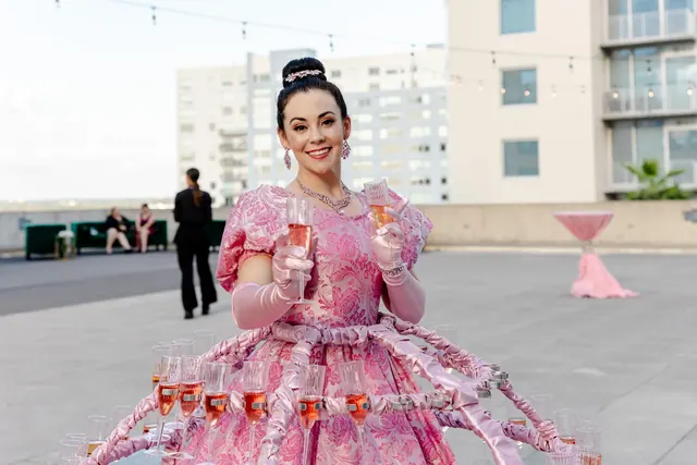 Performer in pink welcoming guests with drinks at the 2025 Goodness Gala