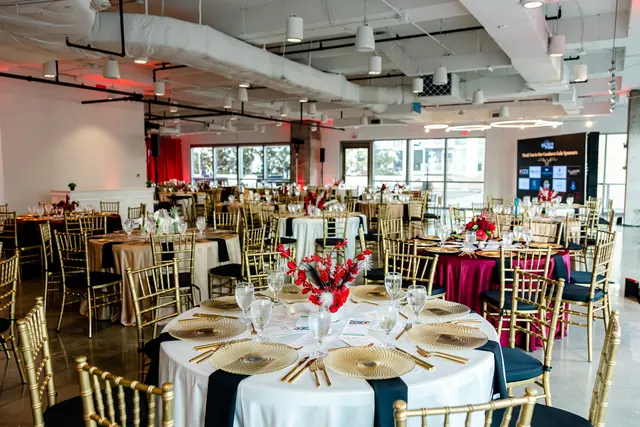 Dining room set with gold chairs and red floral arrangements at the 2026 Goodness Gala