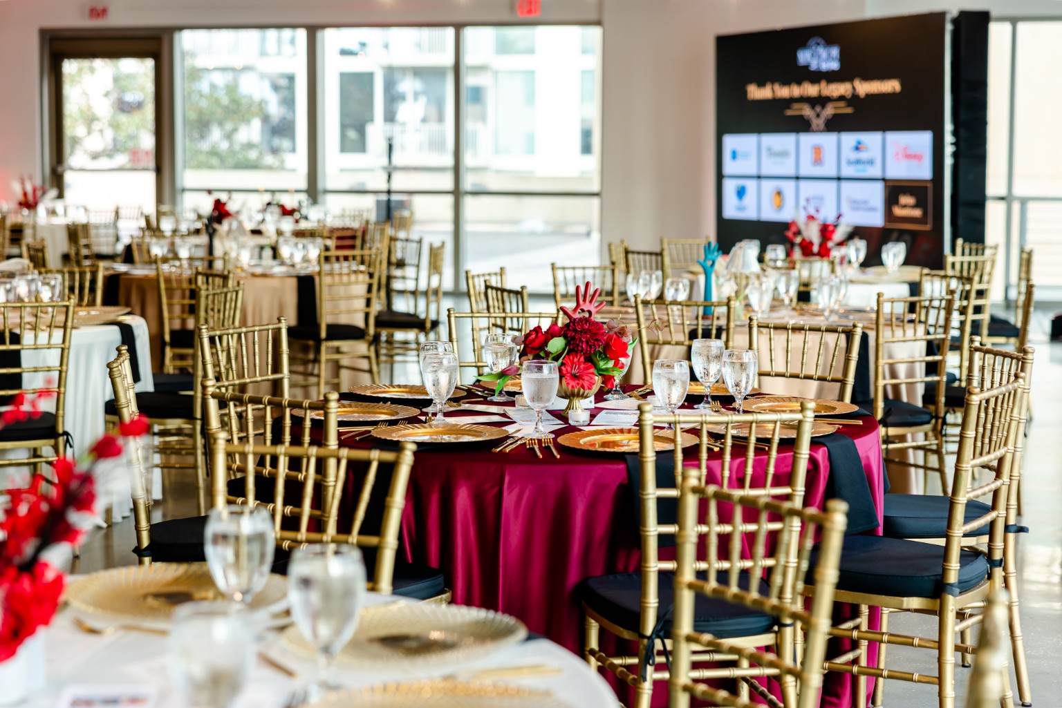 Red floral centerpieces, gold chairs and gold place settings at the 2026 Goodness Gala