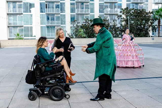 Guests talking with a performer in green on the rooftop at the 2025 Goodness Gala